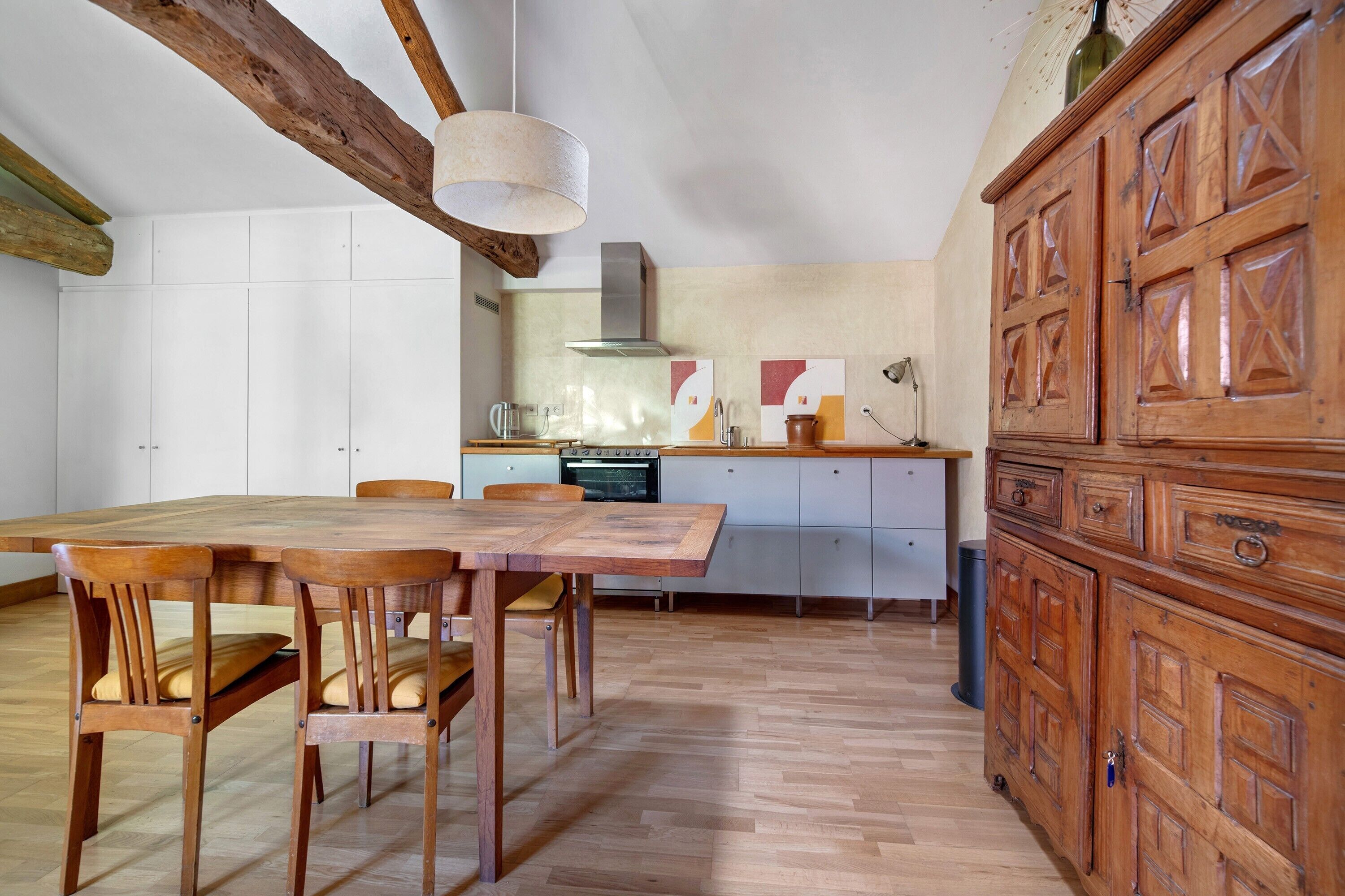 Een ruime keuken met houten meubels, een eettafel en kastjes.
