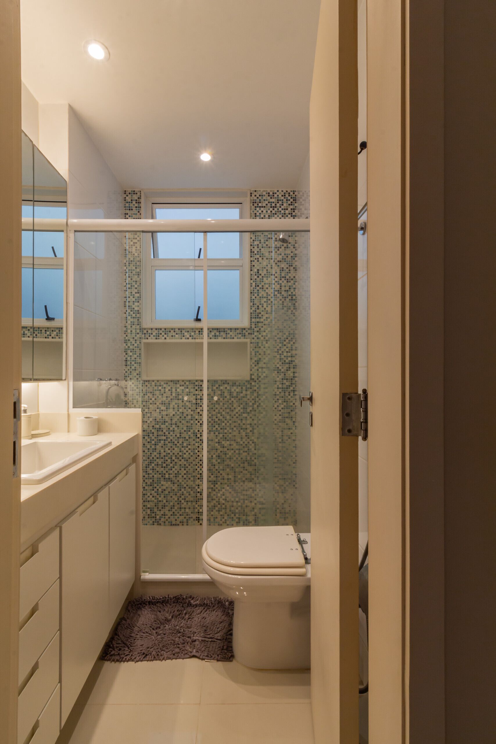 A compact bathroom with a shower, toilet, and a mirror above the sink.