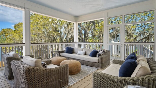A covered outdoor seating area with wicker furniture and a view of trees. - Dieu Not Disturb 5 Bedroom Home (Georgetown)