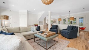A modern living room with a sofa, armchair, and coffee table, a dining area with a table and chairs, and a kitchen in the background. - Dieu Not Disturb 5 Bedroom Home (Georgetown)