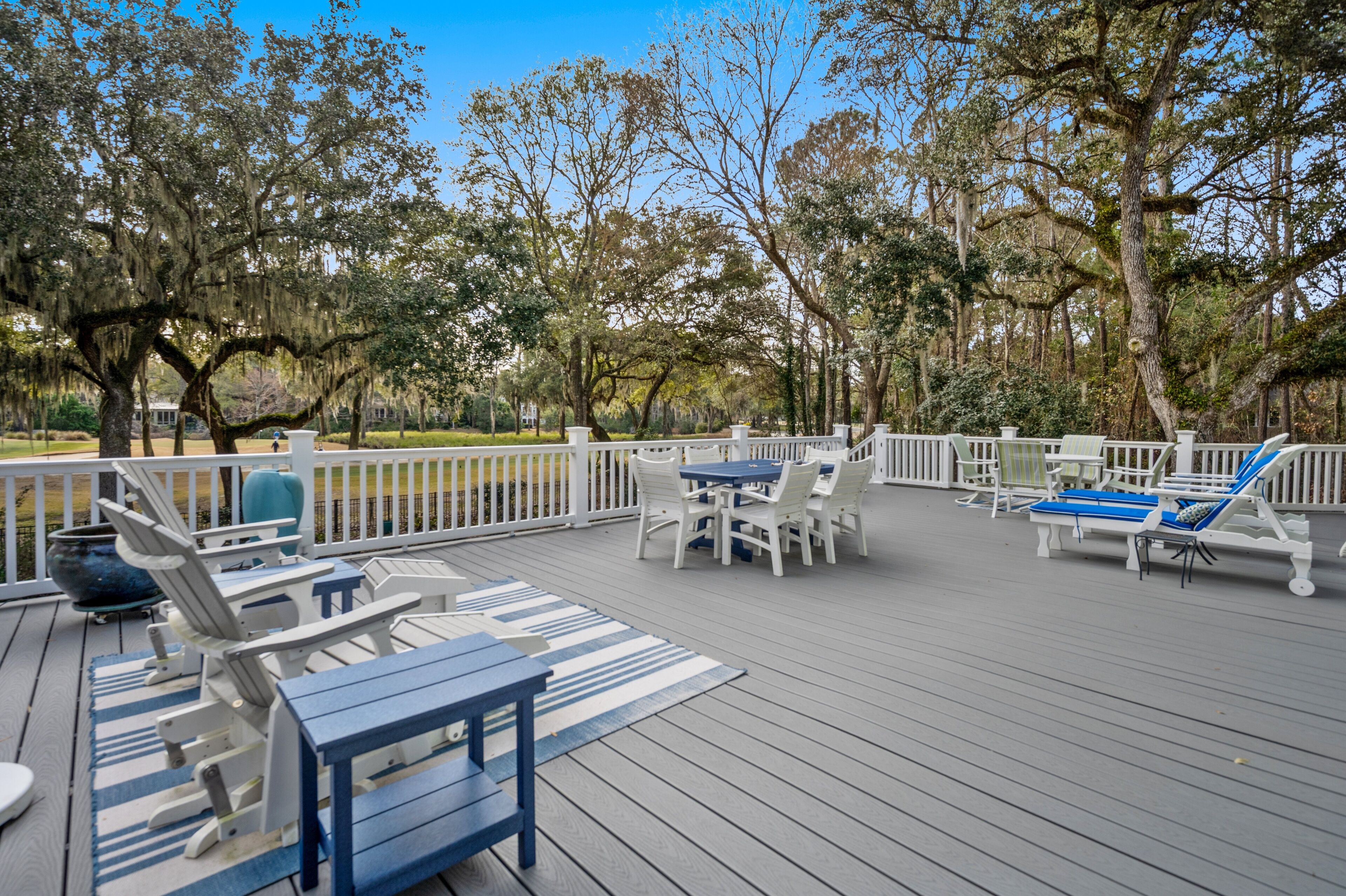A deck with outdoor furniture, including chairs, tables, and a lounge chair.