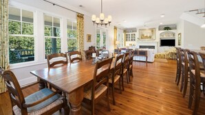 A spacious dining area with a large wooden table and chairs, a chandelier, and large windows with curtains. - Knock On Wood 5 Bedroom Home (Georgetown)