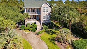 A two-story house with a balcony, surrounded by lush greenery and palm trees. - Knock On Wood 5 Bedroom Home (Georgetown)