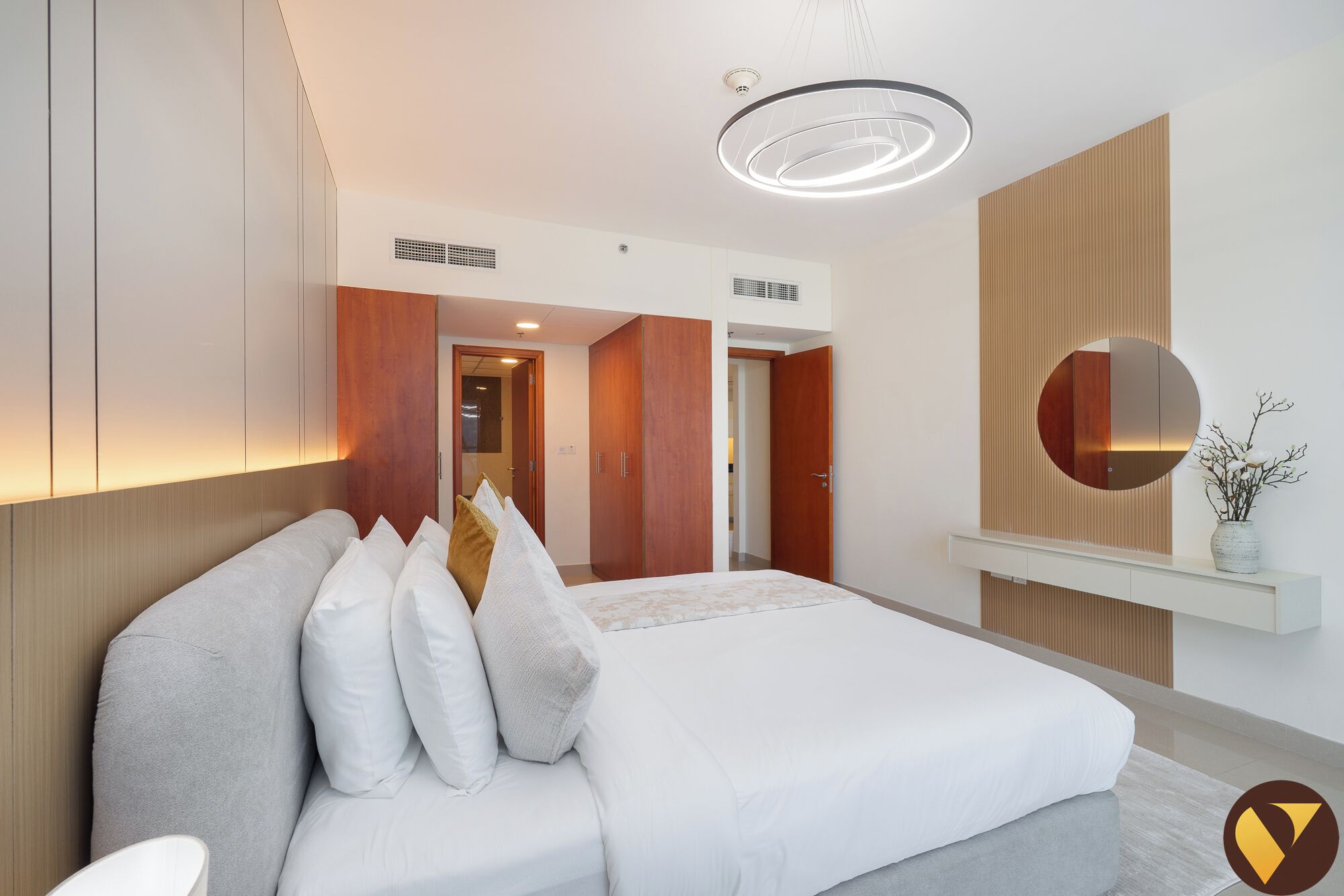 Ein modernes Hotelzimmer mit einem großen Bett, einem runden Spiegel und einer Deckenleuchte.