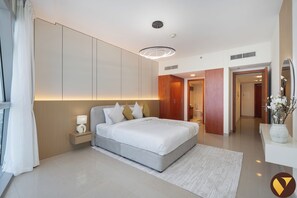 A modern hotel room with a large bed, a bedside table with a lamp, a wardrobe, and a bathroom visible through an open door. - Vogue Park Tower near DIFC Metro Station (Dubai)