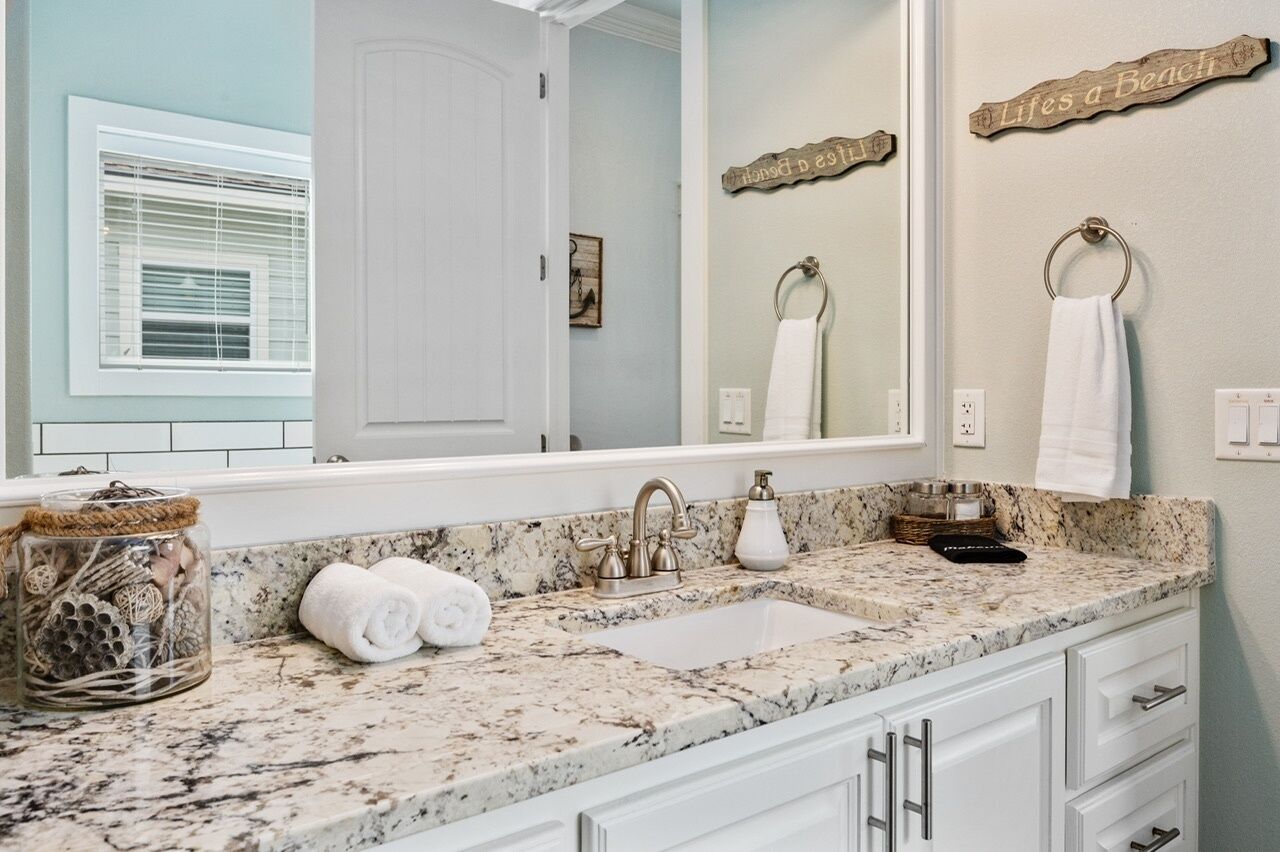 A bathroom with a large mirror, a sink with a faucet, and a towel rack.