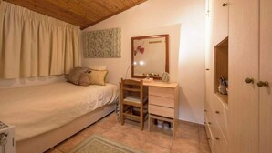 Ein Schlafzimmer mit einem Bett, einem Holztisch, einem Spiegel und einer Tür.