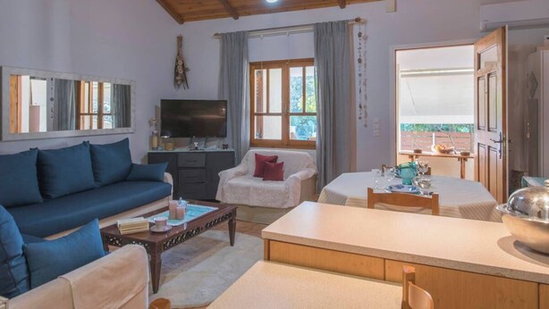 Ein gemütliches Wohnzimmer mit einer Couch, einem Sessel und einem Essbereich mit Tisch für zwei Personen.
