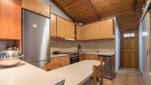 Eine Küche mit Holzausbau, einem Edelstahlkühlschrank, einer gefliesten Spritzschutzwand und einer Holzzieldecke.