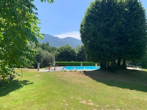 A pool area with a clear view of mountains in the background, surrounded by trees and grass. - Casa Valentina - Pool, Tennis & AC - Lake Maggiore (Montegrino Valtrvaglia)