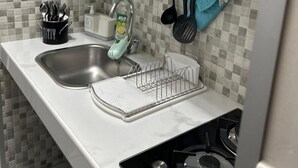Una cocina con un lavamanos, estufa y diversos utensilios colgados en la pared.