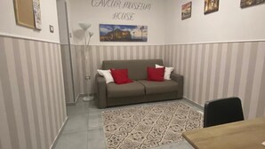 Una habitación con un sofá gris, un tapete estampado, una mesa de madera y una pared con un cartel que dice 'Cavour Museum House'.