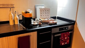 Una cocina compacta con armarios de madera, encimera negra, horno de acero inoxidable y cafetera.