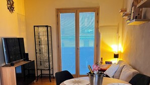 Un comedor con una mesa redonda de madera, sillas negras y un cubo metálico con una botella.