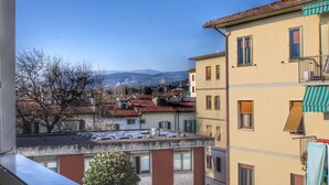 Un edificio residencial con varios balcones, vistas despejadas del vecindario y una cadena montañosa distante.
