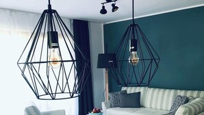 A modern living room with a wooden dining table, two black hanging pendant lights, a sofa, and a coffee table. - Wanderlust Chiemgau (Bad Endorf)