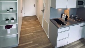 A modern kitchen with white cabinets, a wooden floor, and a built-in oven. - Wanderlust Trier (Trier)