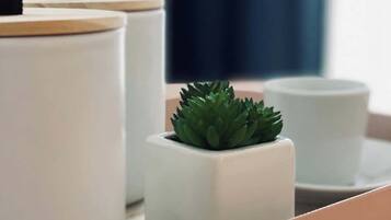 Een modern interieur met witte, cilindervormige bakken met houten deksels, een klein vetplantje en een witte kop op een dienblad.