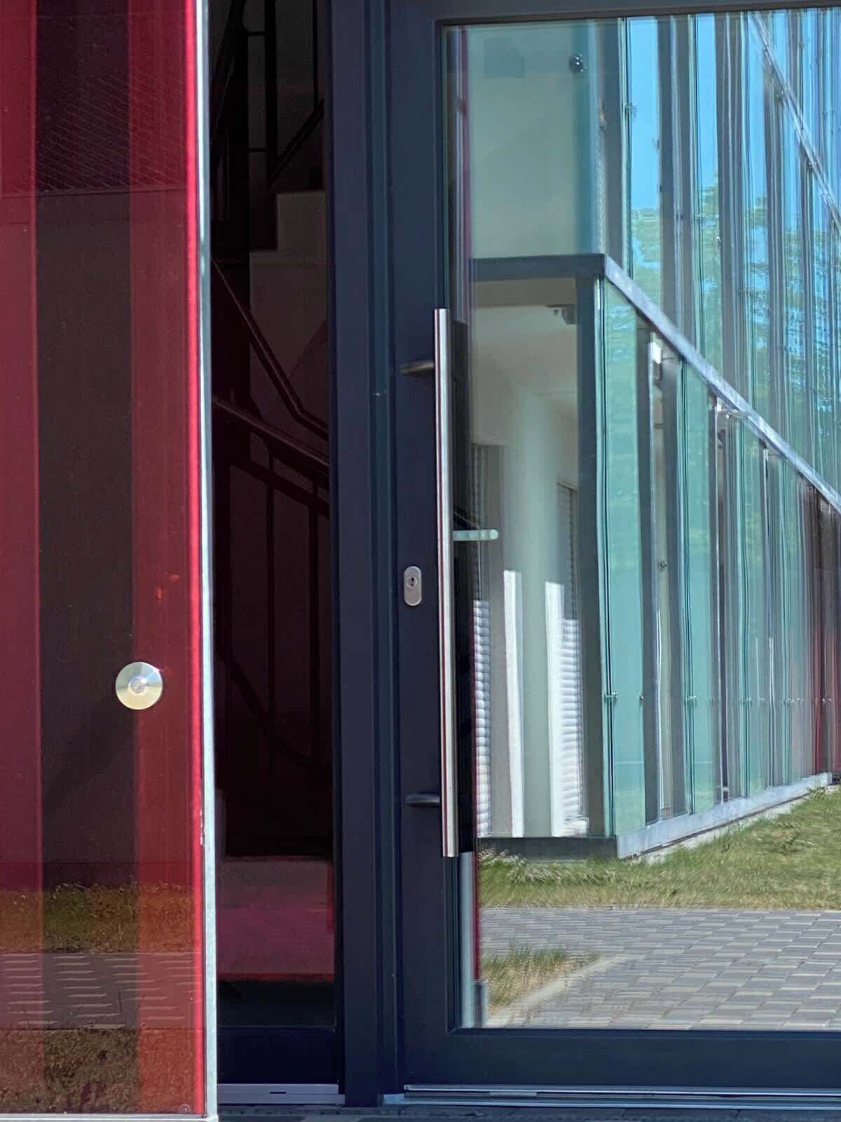 A modern building entrance with a glass door and a metal handle.