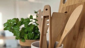 A white ceramic mug with wooden utensils on a kitchen counter.