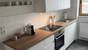 A modern kitchen with white cabinetry, a wooden countertop, and a built-in oven.