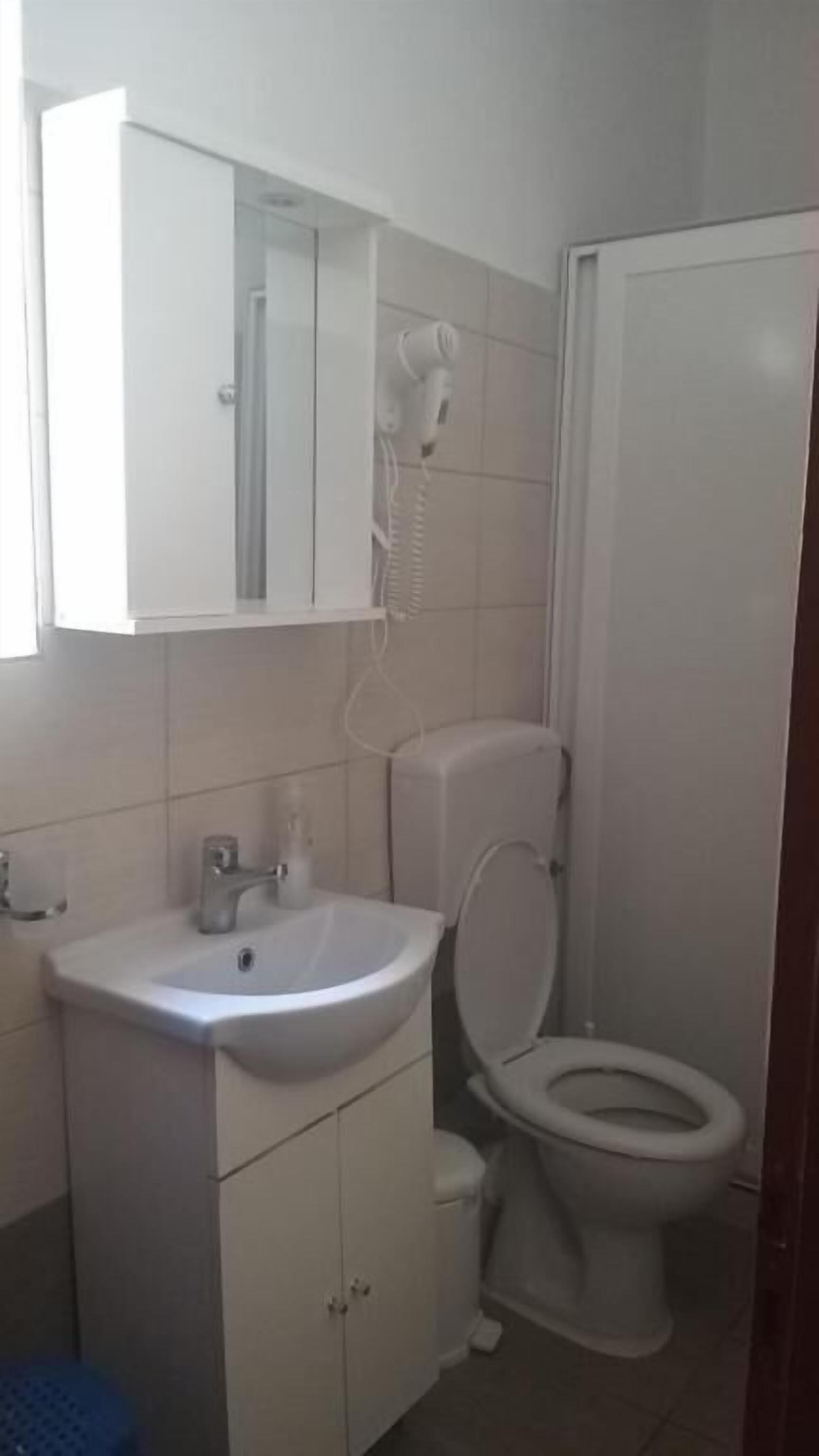 Een badkamer met een wit wastafelmeubel, spiegel en toilet.