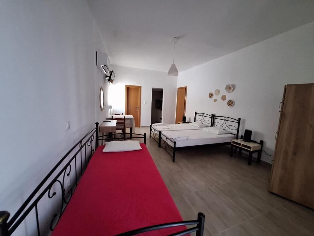 Een slaapkamer met een rood tapijt, twee bedden, een bureau en een kledingkast.