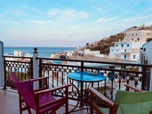 A balcony with a table and chairs overlooking a coastal town. - Nikos Hotel  (Diafani)