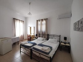 Un dormitorio limpio y bien iluminado con dos camas individuales, un escritorio pequeño y un radiador.