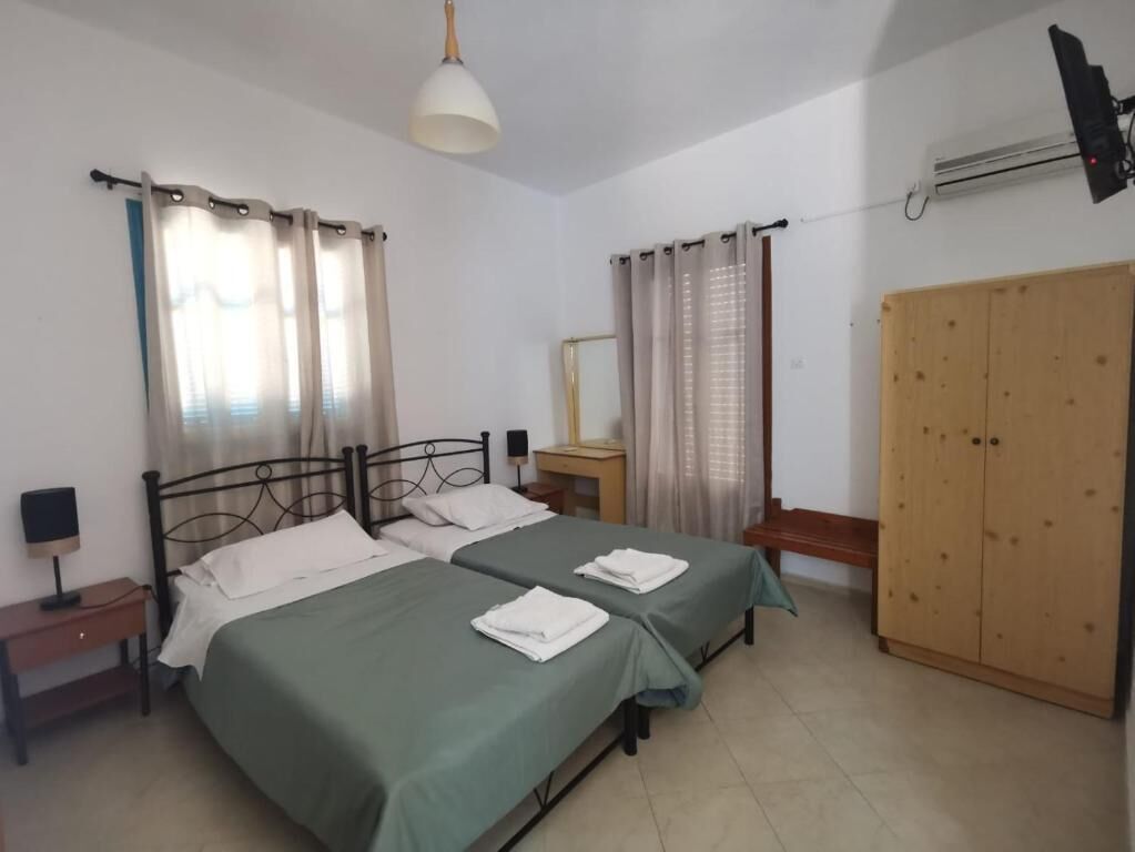 Una camera da letto con due letti, un armadio, un comodino con una lampada e una finestra con tende.