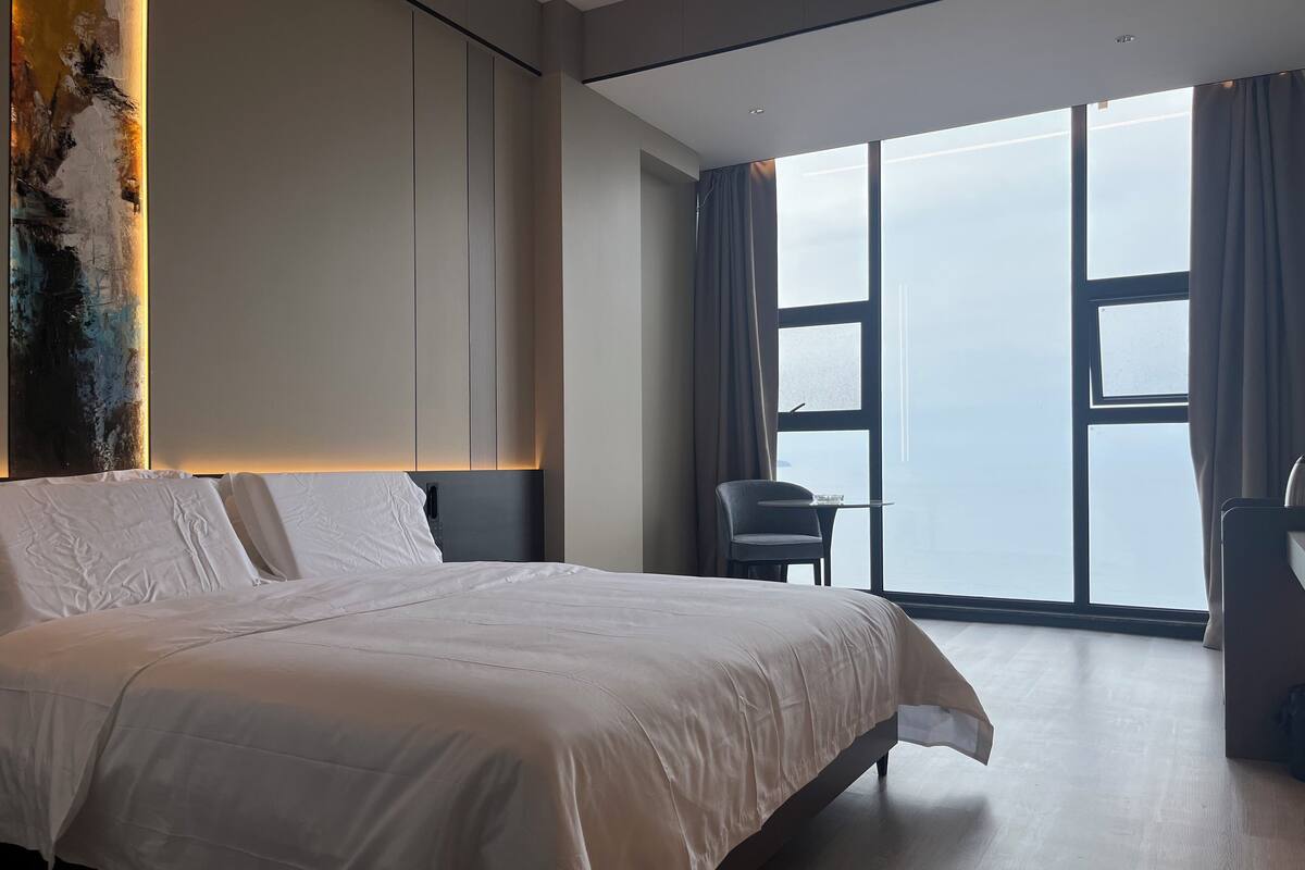 A modern hotel room with a large bed, a small table, and a chair.