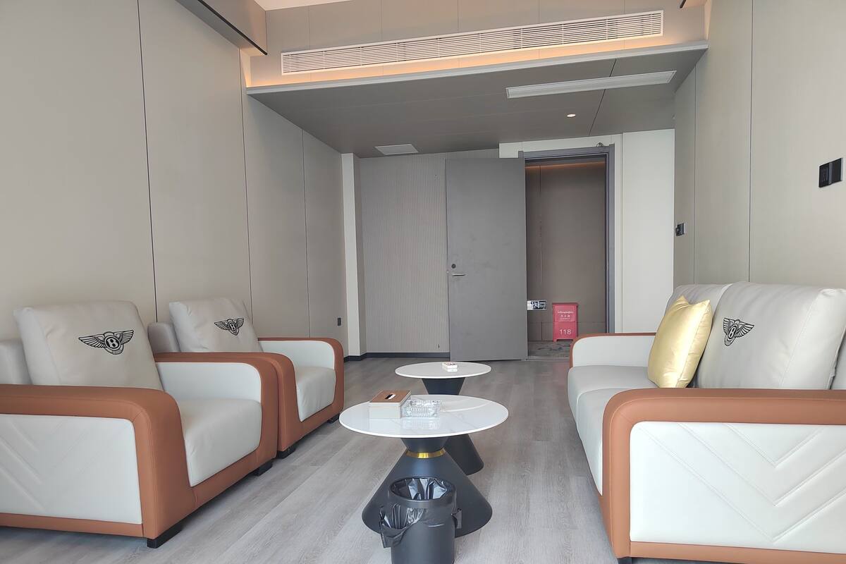 A modern hotel room with two sofas, a small table, and a trash bin.