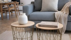 En moderne stue med en grå sofa, en hvid vase og en bog med titlen 'Mediterranean Living' på et rundt bord.