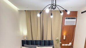 Ein ordentlich eingerichtetes Schlafzimmer mit Bett, Nachttisch, Sessel und einem kleinen Tisch mit einer Vase.