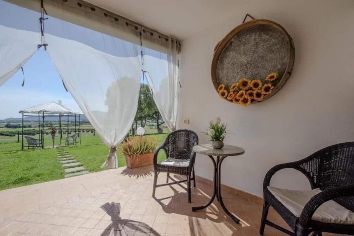 Un balcon avec des fauteuils en osier, une petite table et un pot de fleurs.