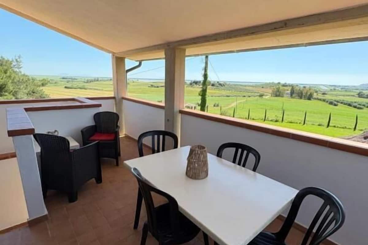 Un balcon avec une table et des chaises, un petit coin bar et une vue sur la campagne.