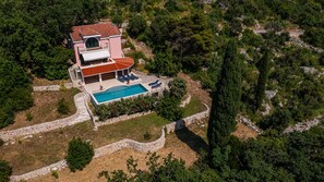 A two-story house with a swimming pool, surrounded by trees and a stone wall. - Grand view Orasac by Villas Guide (Dubrovnik)