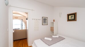 A bedroom with a bed, a bedside table, a wardrobe, a framed picture, and a view through an open door. - Grand view Orasac by Villas Guide (Dubrovnik)