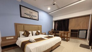 A hotel room with a large bed, a desk, and a refrigerator. - Hotel Silver Bell (Lucknow)
