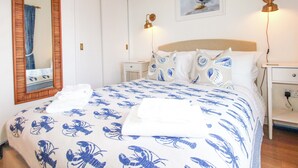 A bedroom with a bed, a mirror, a painting, bedside lamps, and a nightstand. - 4 The Elms (Salcombe)