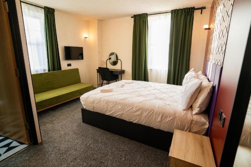 A hotel room with a bed, a desk, a chair, and a television.