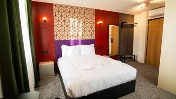 A hotel room with a bed, a nightstand, a wardrobe, and a mirror.
