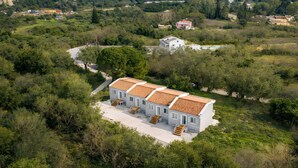 A white building with a tiled roof, surrounded by greenery and hills, with a clear view of the landscape. - Delux Maisonete 3 Country House with Mountain View, Private Garden and Wi-Fi (Κυρά Χρυσικού)