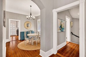 A spacious dining area with a round table and chairs, a chandelier, and a large mirror on the wall. - Stunning Home in Savannah’s Design District, Near Forsyth by Lucky Savannah (Savannah)