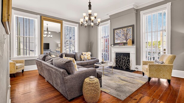 Una sala de estar con un sofá gris, un sillón amarillo y una mesa redonda de madera.