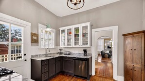Una cocina con armarios oscuros, encimera de granito y suelo de madera.