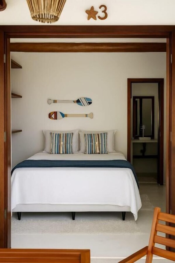 Ein Schlafzimmer mit einem Bett, Kissen, einem Holzstuhl, einer Holztür und einer sternförmigen Dekoration an der Wand.