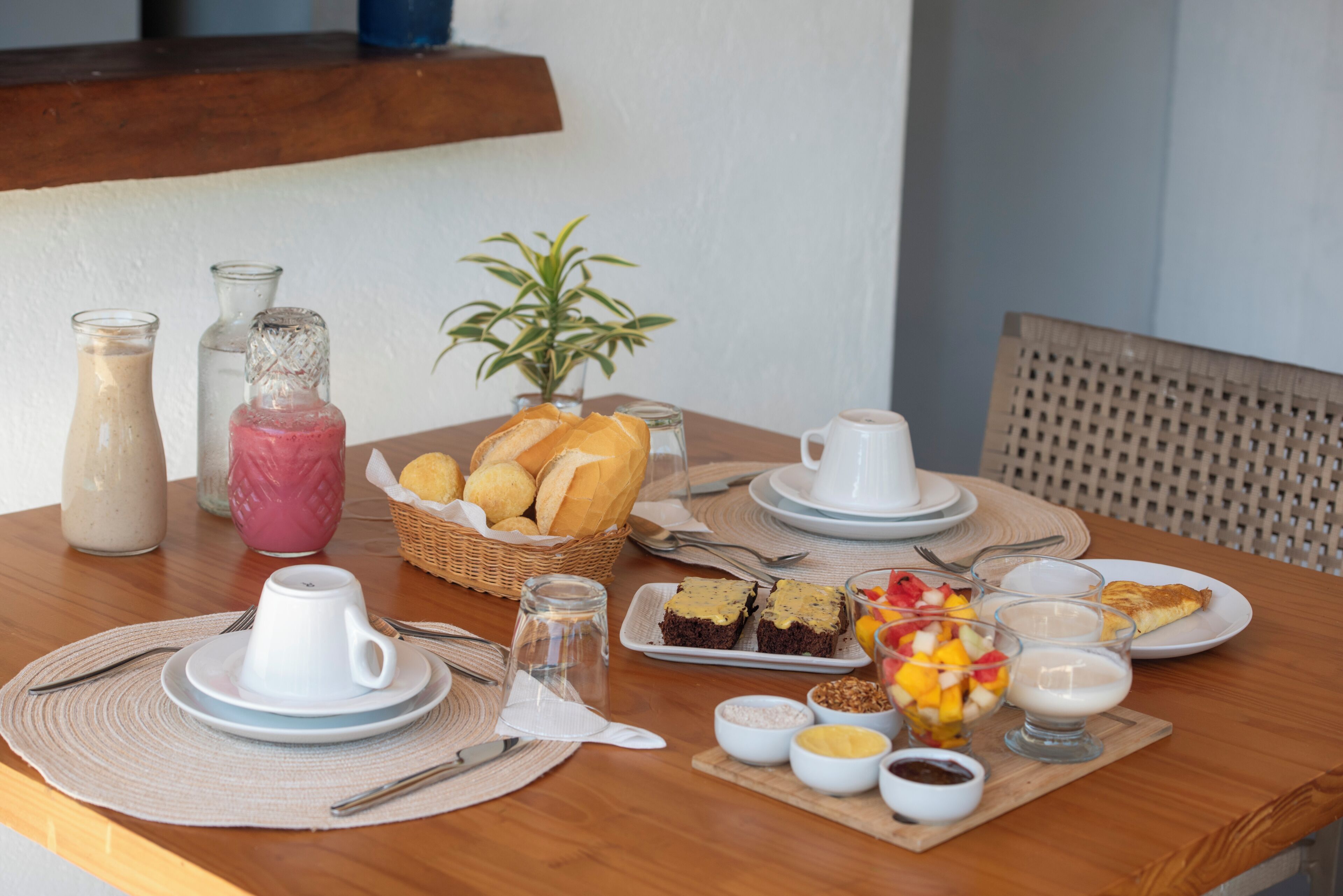 Una mesa de desayuno con platos, tazas y diferentes alimentos.