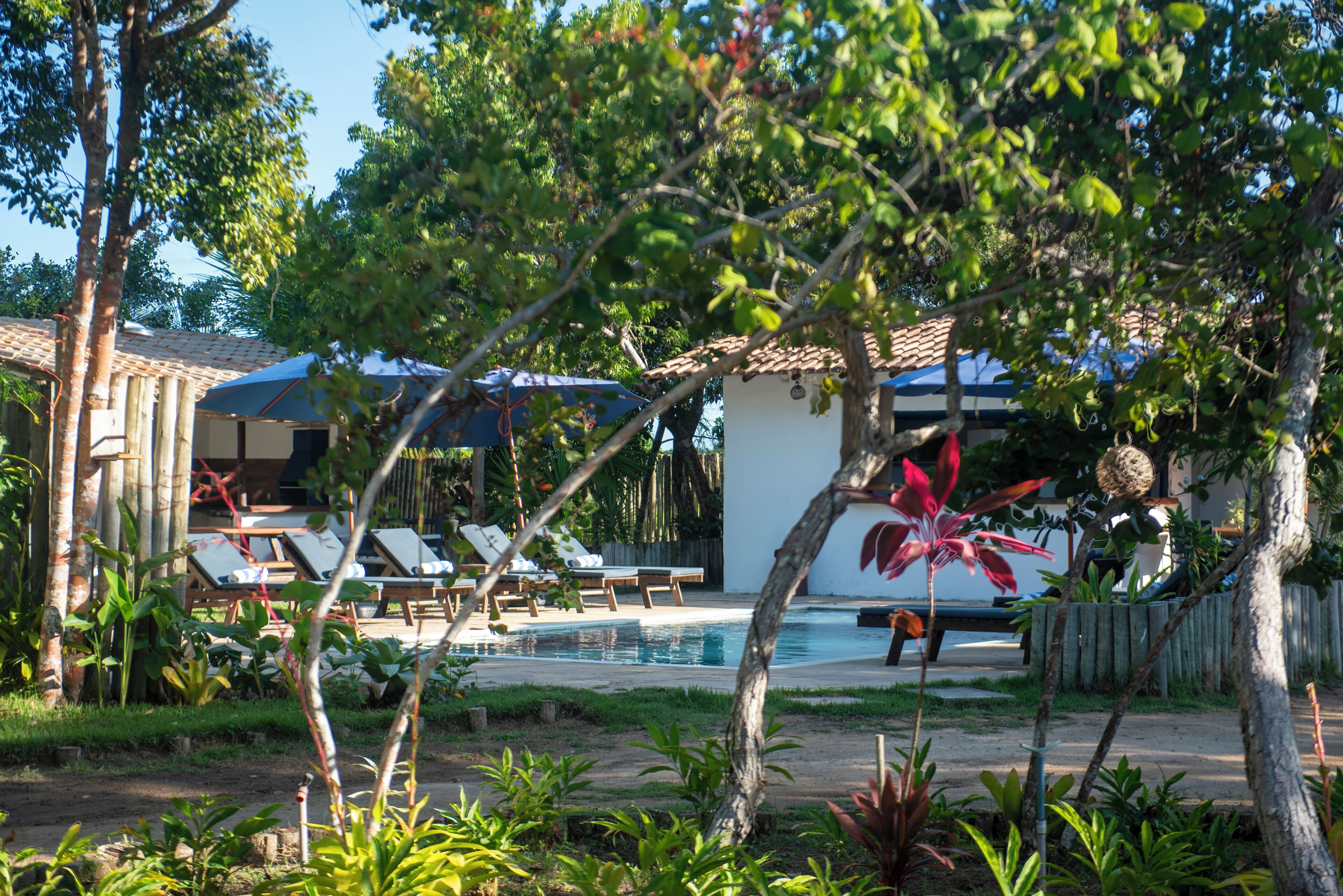 A pool area with lounge chairs, a small building, and a wooden fence.