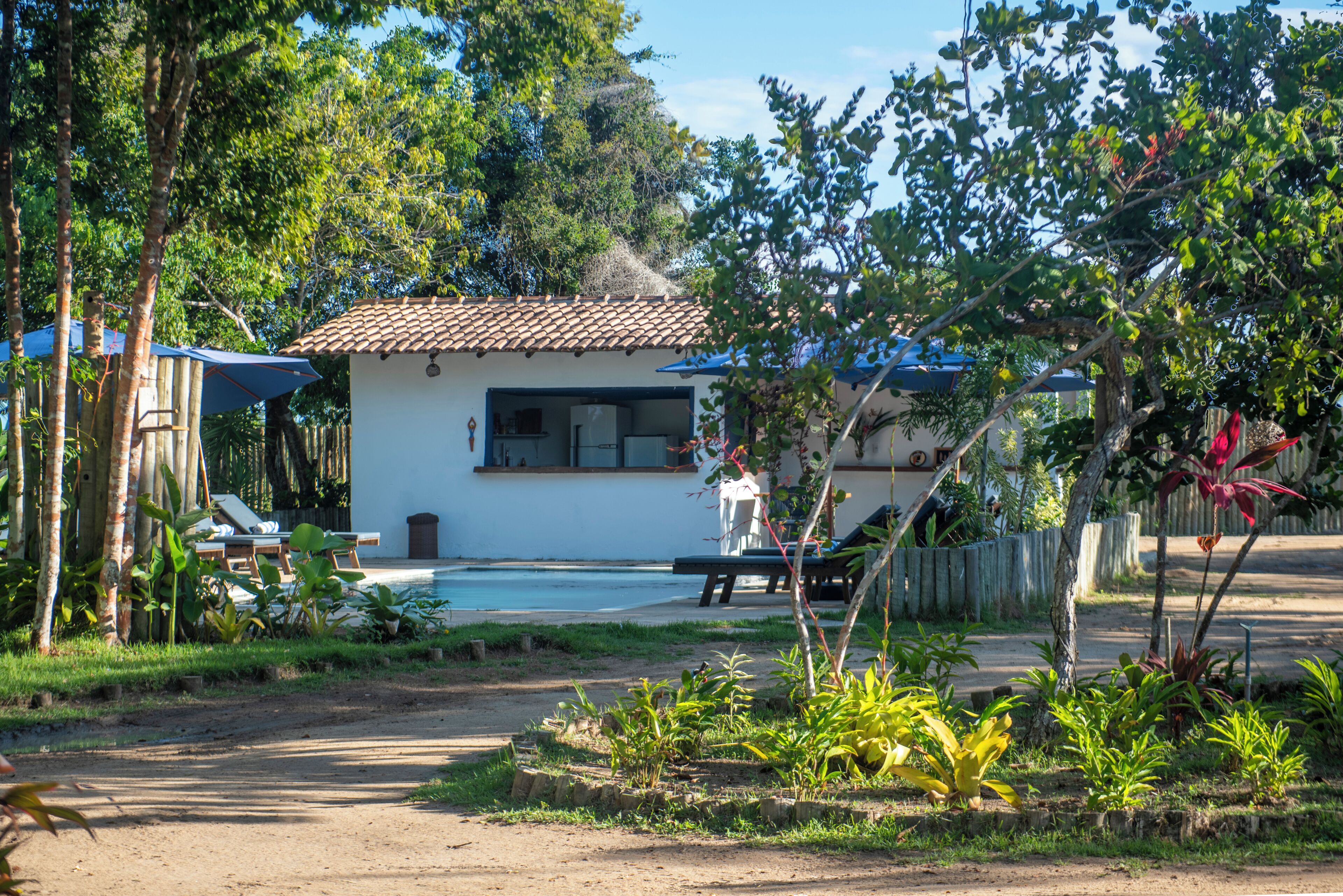 Une maison avec un toit en tuiles, une piscine et un jardin où poussent différentes espèces de plantes.